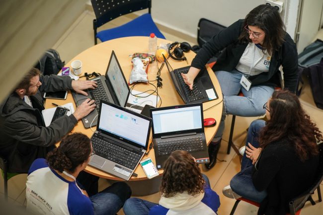 A group of people sitting around a round table with computers