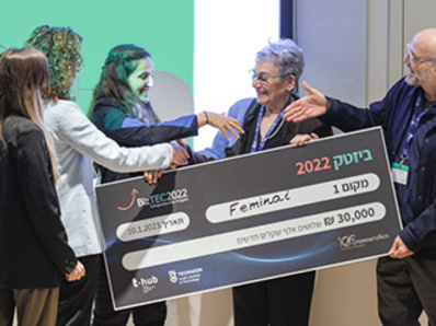 Five people standing holding a check awarded as a prize and shaking hands