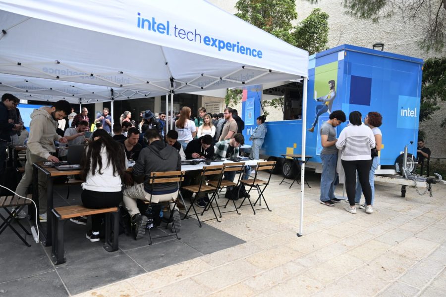 A group of people standing and sitting under a gazebo with the Intel logo on it