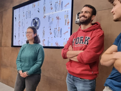 Three people standing near a screen and smiling